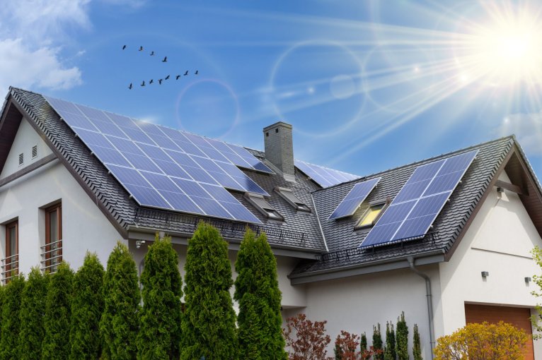 Solar panels on a gable roof. Beautiful, large modern house and solar energy. Rays of the sun.