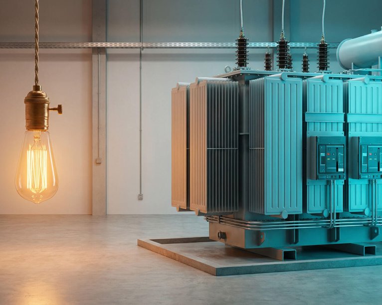 Un gran transformador eléctrico industrial en una sala técnica junto a una bombilla de filamento encendida, representando el suministro de energía para tarifas de luz de grandes cuentas.